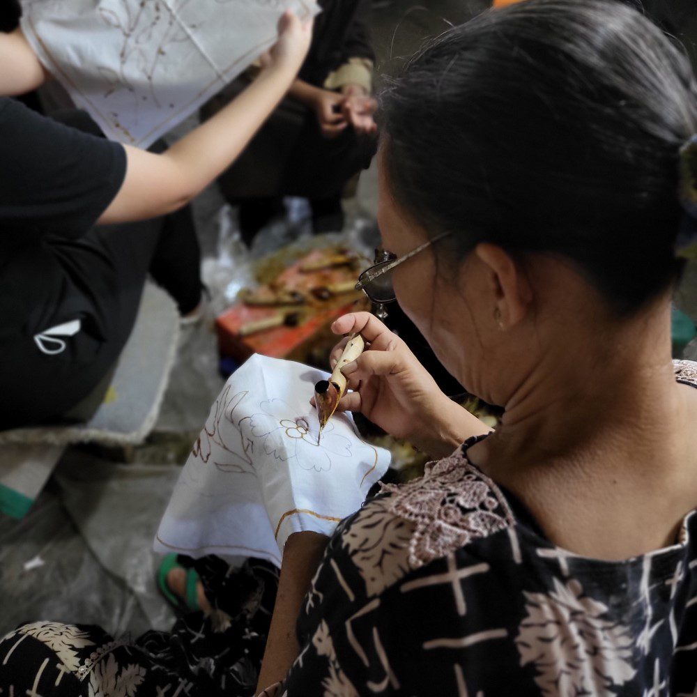 A woman is designing batik or called "mencanting"